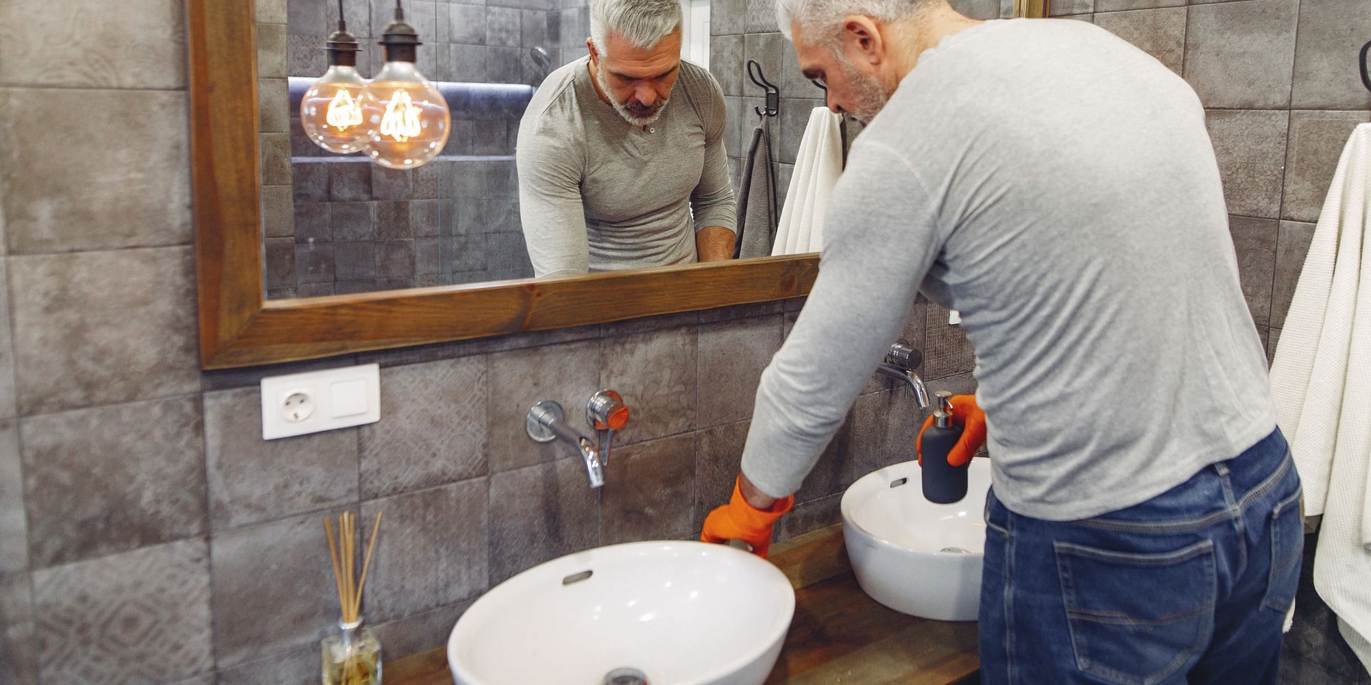 Fontanero trabajando en el lavabo de un cuarto de baño