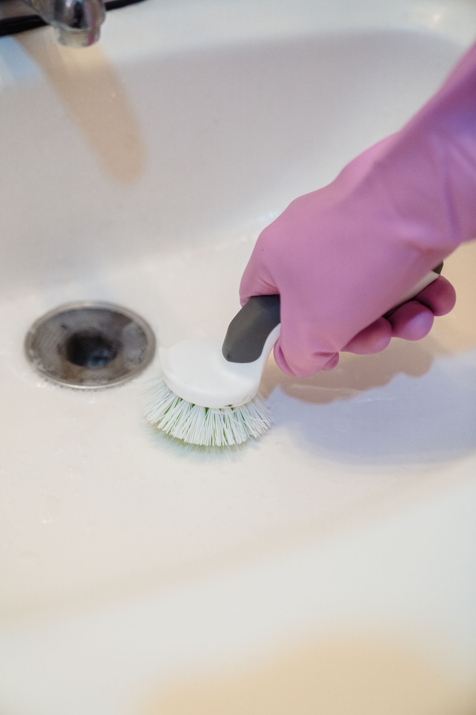 Brossage de la bonde d'un lavabo lors d'un nettoyage en profondeur